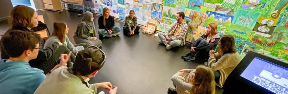 Ein Dutzend Lehrer:innen und Schüler:innen arbeiten kreativ und zugewandt zusammen.